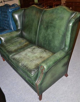 Lot 424 - A modern green leather wing back double settee