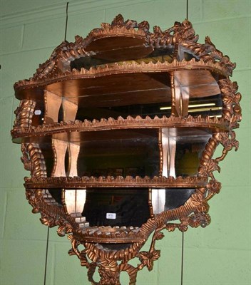 Lot 476 - A carved giltwood wall shelf with Rococo style swags and bows and mirrored back