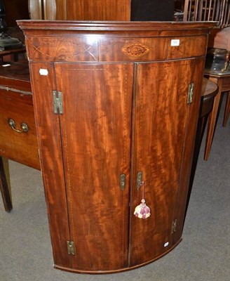 Lot 565 - A Georgian inlaid bow front corner cupboard