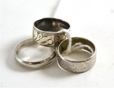 Lot 100 - A platinum band ring, a patterned band ring stamped 'PLATINUM' and another band ring
