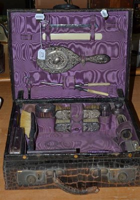 Lot 279 - A crocodile skin cased travelling vanity or toilet set with cut glass and silver mounted fittings