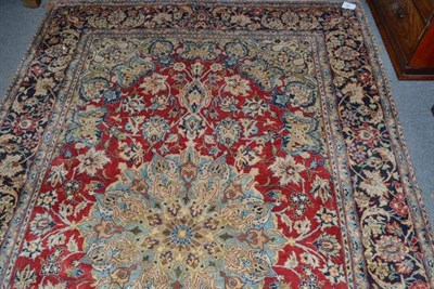 Lot 667 - A Persian carpet, possibly Kashan, the tomato red field of scrolling vines around a pole...