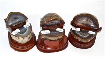 Lot 48 - Three geodes, each cut in half displaying a polished surface, each in a carved stand