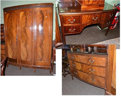 Lot 540 - A mahogany bow fronted three piece bedroom suite comprising triple wardrobe, chest of drawers...