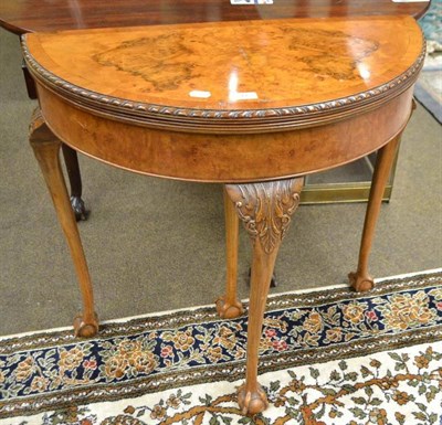 Lot 566 - A figured walnut demi lune fold over card table