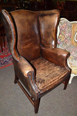 Lot 616 - A Georgian-style brown leather upholstered wing armchair