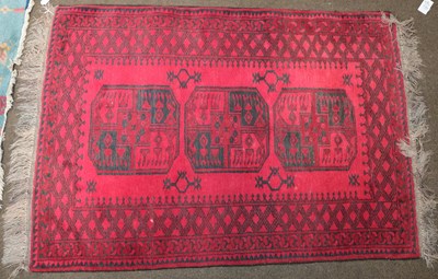 Lot 1180 - Afghan rug, the crimson field with three...