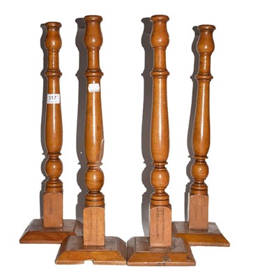 Lot 317 - A set of four tall treen candlesticks (from a...