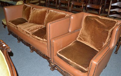 Lot 464 - A 19th century sofa of a carved oak base with brown leather upholstery and a similar wing armchair