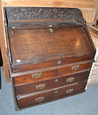 Lot 515 - An 18th century and later oak bureau with carved back rail