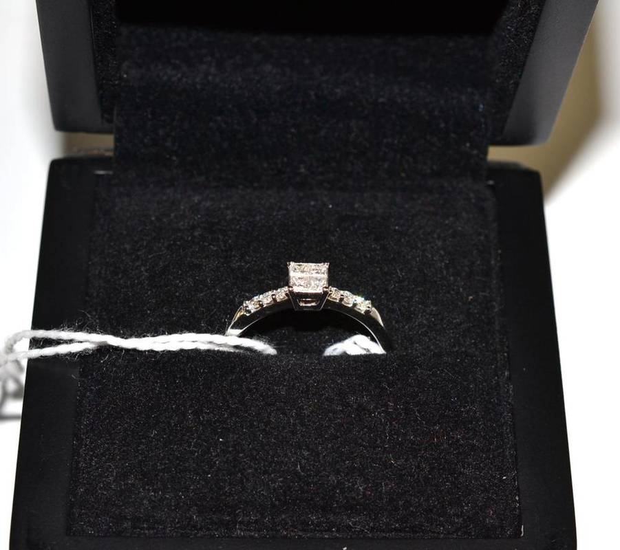 Lot 50 - An 18ct white gold diamond ring, four princess cut diamonds to the centre and round brilliant...