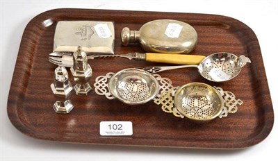 Lot 102 - A silver strainer, two EPNS strainers, two silver pepperettes, a silver oval shaped hip flask,...