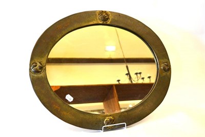 Lot 917 - A Liberty & Co Oval Patinated Brass Wall Mirror, with four riveted embossed Celtic roundels,...