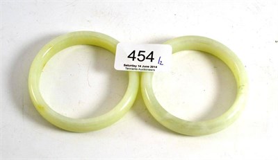 Lot 454 - Two Chinese carved pale green jade type bangles