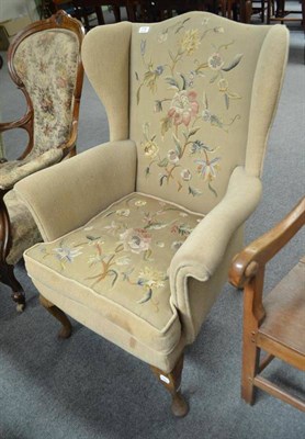 Lot 716 - A cream upholstered wing armchair with needlework back and seat