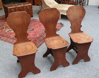 Lot 1194 - A set of three late Georgian oak hall chairs