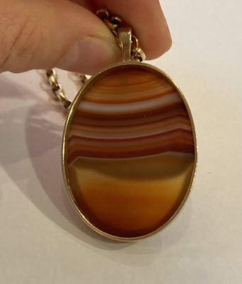 Lot 279 - A 9 carat gold banded agate pendant on a 9...