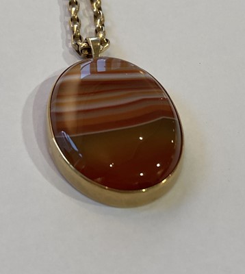 Lot 279 - A 9 carat gold banded agate pendant on a 9...