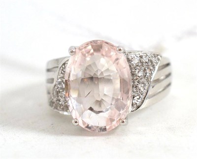 Lot 220 - An 18ct white gold morganite ring, the oval mixed cut morganite with white topaz on the...