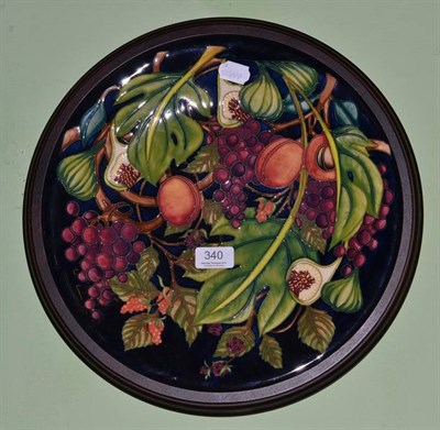 Lot 340 - Modern Moorcroft charger decorated with fruit, in a wooden frame