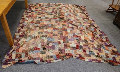 Lot 1306 - A large patchwork bed cover made up of batik...