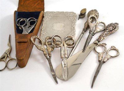 Lot 323 - Leather scissor case with three pairs of steel stork scissors, small fish pin cushion, silver...