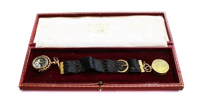 Lot 140 - A coin locket suspended from a black ribbon...