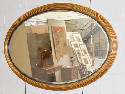 Lot 1326 - An oval hanging wall mirror in reeded gilt...