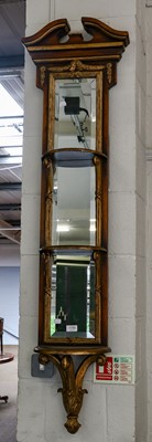 Lot 1150 - A reproduction parcel-gilt mirror of slender...