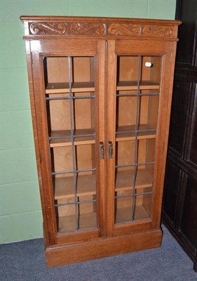 Lot 404 - A blonde oak bookcase with leaded glazed doors