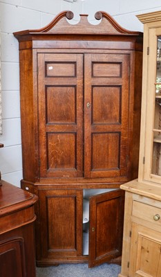 Lot 1133 - A George III oak standing corner cupboard with...