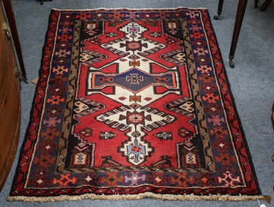 Lot 1015 - A tribal rug, raspberry field with ivory...