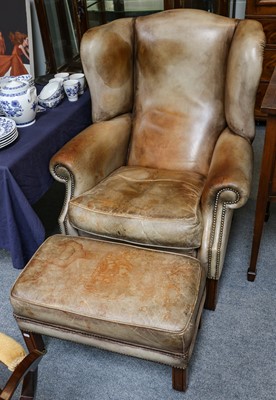 Lot 1239 - A tan leather studded wing back chair on...