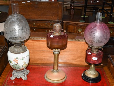 Lot 321 - A Cranberry oil lamp and shade, and two others