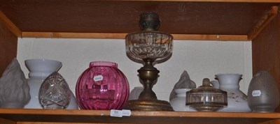 Lot 85 - A shelf of glass oil lamp shades, reservoirs etc