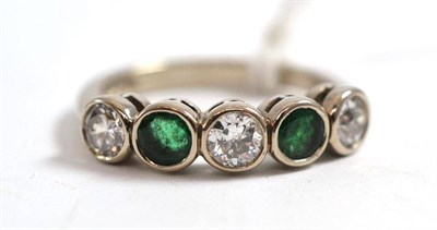 Lot 281 - An 18ct white gold diamond and emerald five stone ring, three round brilliant cut diamonds...