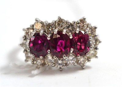 Lot 290 - A ruby and diamond cluster ring, three rubies within a border of round brilliant cut diamonds