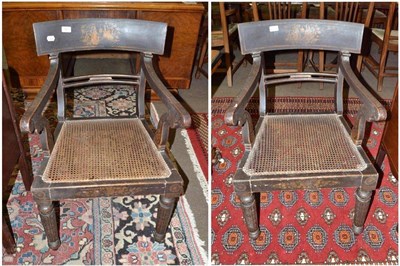 Lot 582 - A pair of Regency ebonised elbow chairs with gilt painted decoration and caned seats