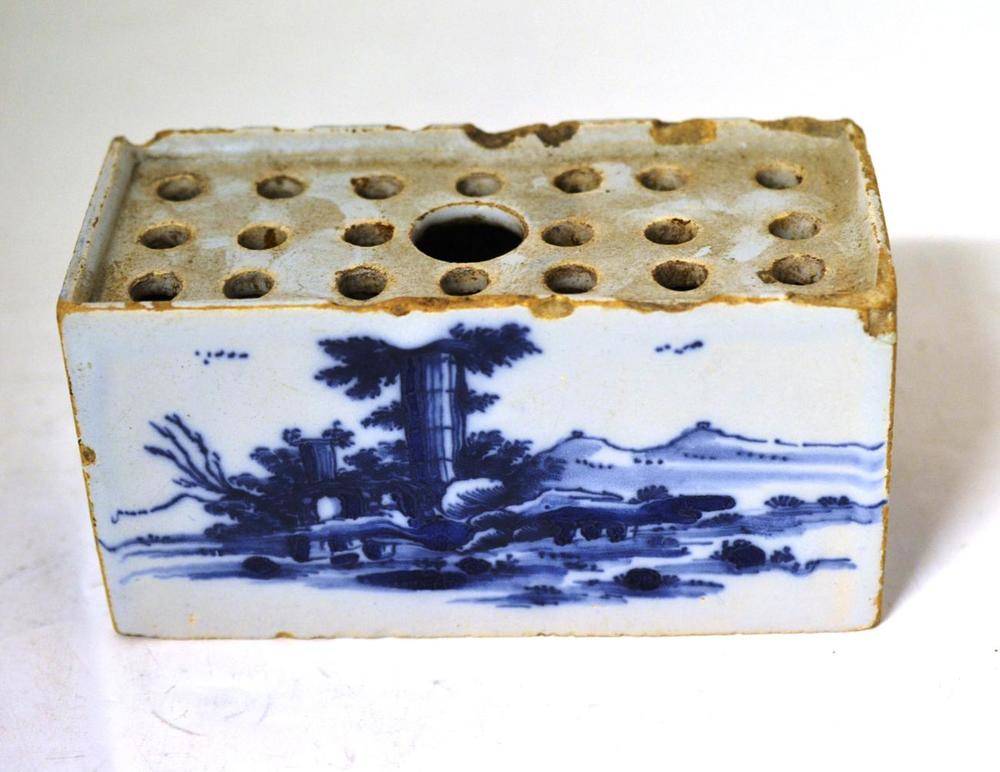 Lot 68 - An English Delft Flower Brick, circa 1750, painted in blue with chinoiserie landscapes, 15cm wide