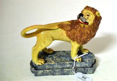 Lot 89 - A Staffordshire Pottery Figure of a Lion, circa 1810, standing four square on a marbled stepped...