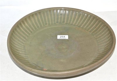 Lot 254 - A heavy stoneware celadon glazed circular dish, with fluted rim, 34.5cm