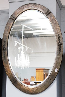 Lot 1159 - An Arts & Crafts Planished Brass Oval Mirror,...