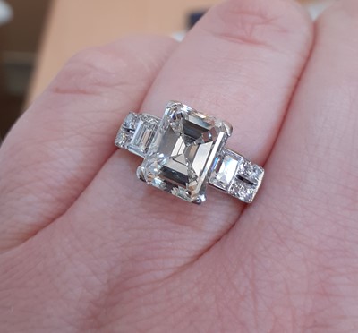 Lot 2320 - A Diamond Ring the central emerald-cut diamond...