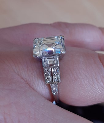 Lot 2320 - A Diamond Ring the central emerald-cut diamond...