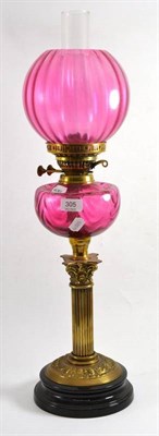 Lot 305 - A 19th century oil lamp with brass Corinthian column and cranberry glass font and shade
