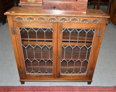 Lot 483 - An oak bookcase with leaded glass cabinet doors