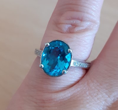 Lot 2020 - A Blue Topaz and Diamond Ring the oval cut...