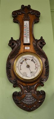 Lot 590 - An aneroid barometer with a carved oak surround