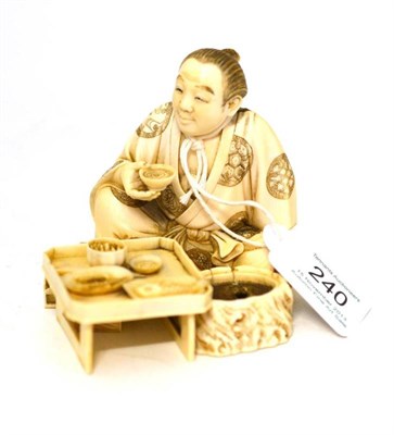 Lot 240 - A Japanese Ivory Okimono, Meiji period, as a seated man holding a bowl, a table before him set with