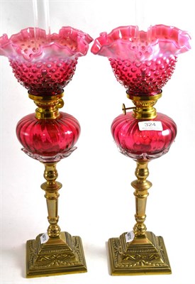 Lot 324 - Pair of brass and cranberry oil lamps